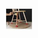 Person staining wooden chair leg, chair elevated on red painter's pyramids for woodworking