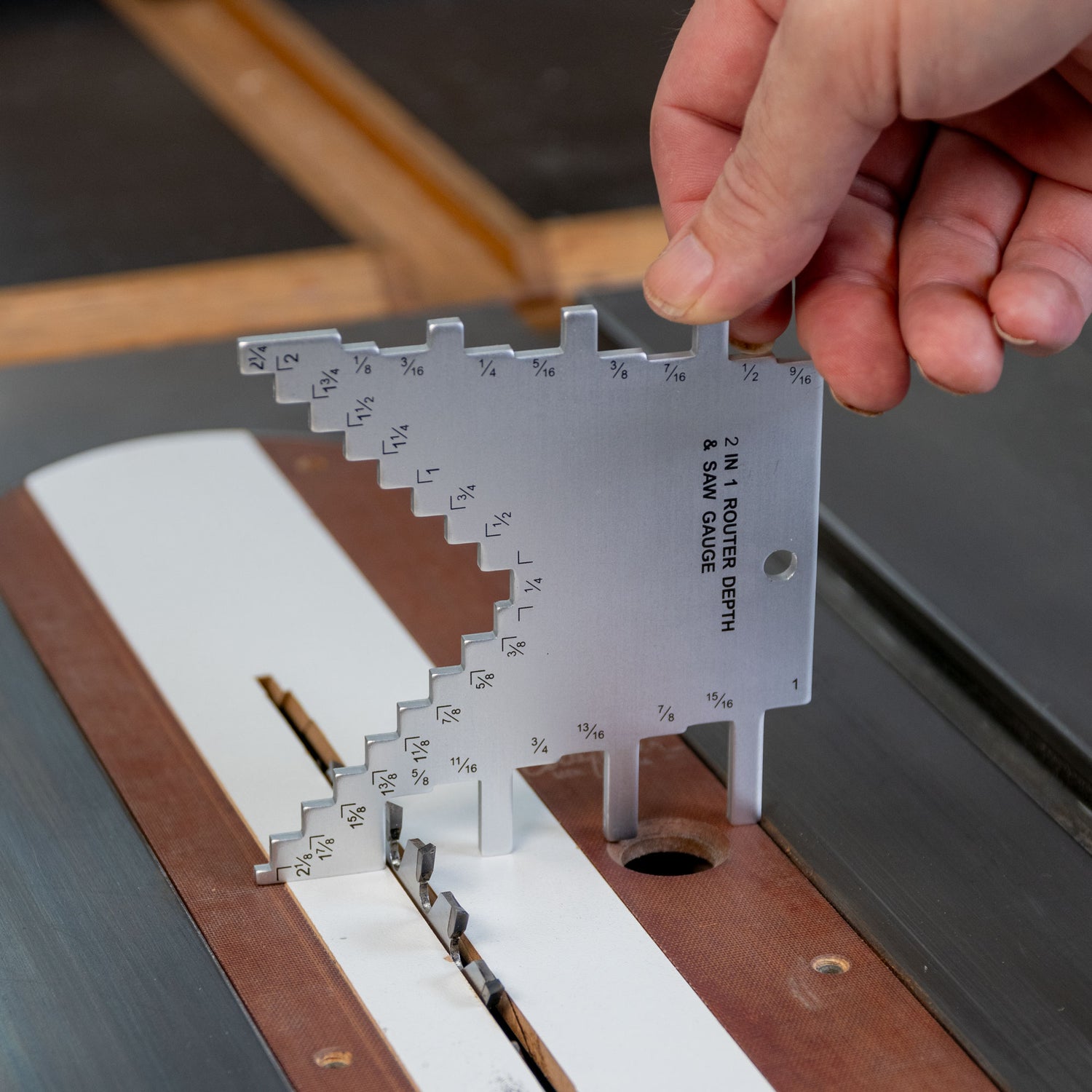 Hand using a metal saw blade and router bit combo depth gauge on a table saw
