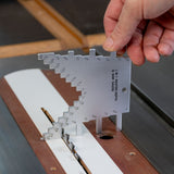 Hand using a metal saw blade and router bit combo depth gauge on a table saw