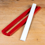 Red zero clearance insert and white strip for miter saw on a wooden workbench