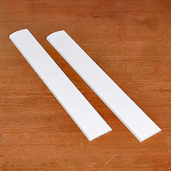 Pair of white jointer knives on wood surface for woodworking tool replacement