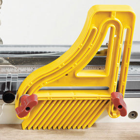 Yellow plastic table saw featherboard mounted on a saw fence for woodworking safety