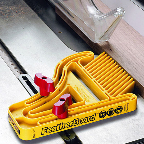 Yellow featherboard for table saw woodworking, securing wood with red knobs and clear blade guard.