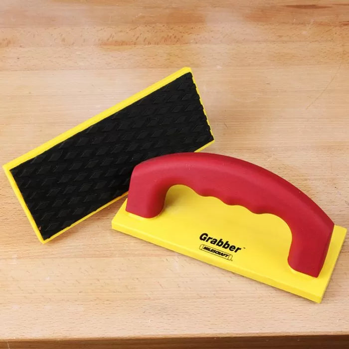 Yellow and red push block with textured rubber grip for woodworking on wooden surface