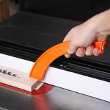 Hand using orange push stick to guide wood on table saw for safe woodworking