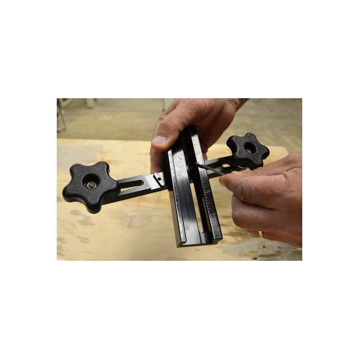 Hands adjusting a woodworking router jig with measurement markings on a workbench