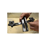 Hands adjusting a woodworking router jig with measurement markings on a workbench