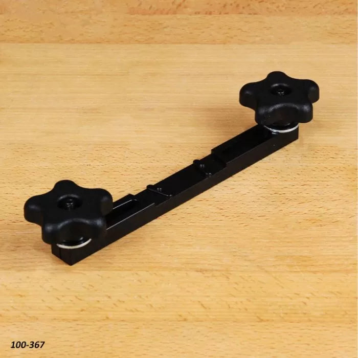 Black woodworking jig with two clamping knobs on a wooden surface