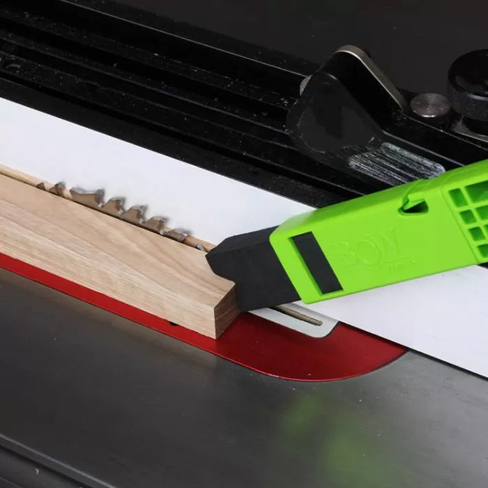 Table saw push stick guiding wood along saw blade for woodworking safety