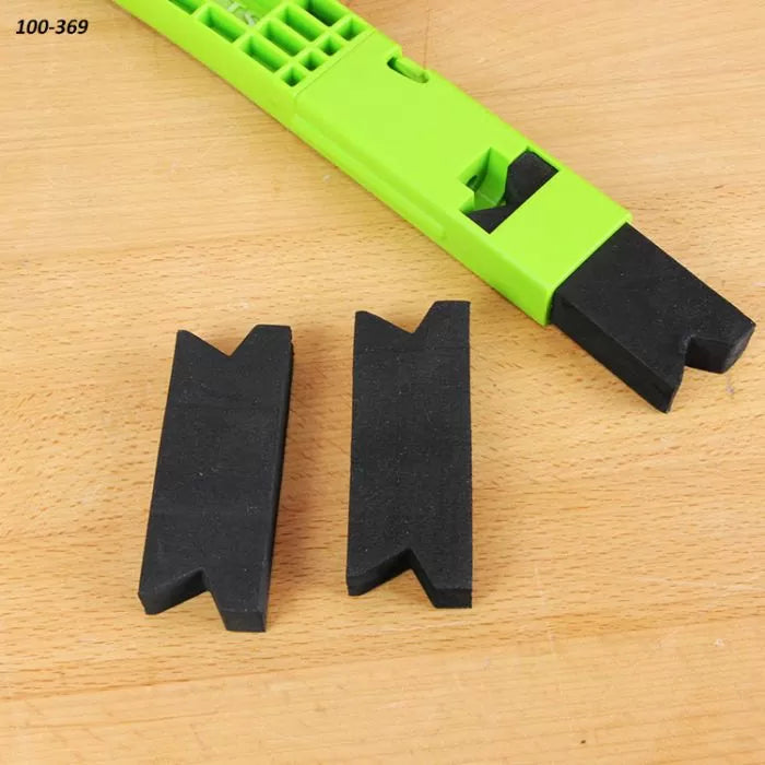 Green woodworking push block with two black V-groove foam inserts on wood surface