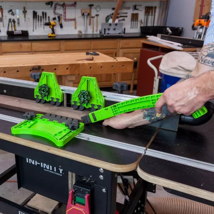 Woodworker using bright green featherboard system on router table for precise cutting