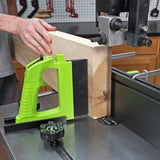 Woodworker using bandsaw and green push block to cut a thick wood board in workshop