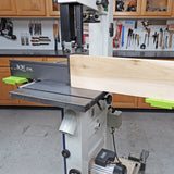 Woodworking bandsaw cutting wide board in workshop, tools and pegboard in background