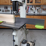 Band saw with resaw fence cutting wood board in woodworking shop