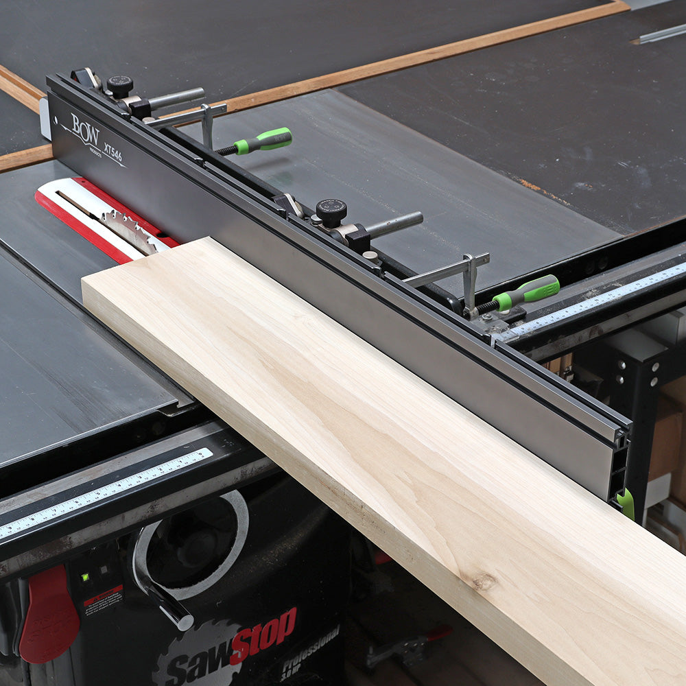 Table saw with fence and push block cutting a wood board in a woodworking shop