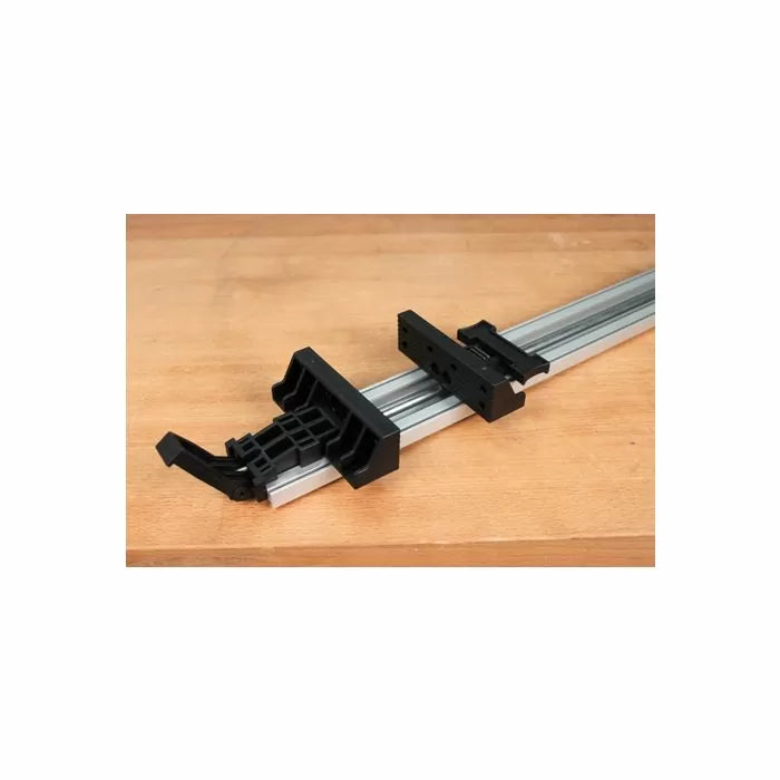 Aluminum woodworking clamp guide rail with black plastic fittings on a wood surface