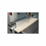 Bandsaw with aluminum fence cutting a wooden board in a woodworking shop
