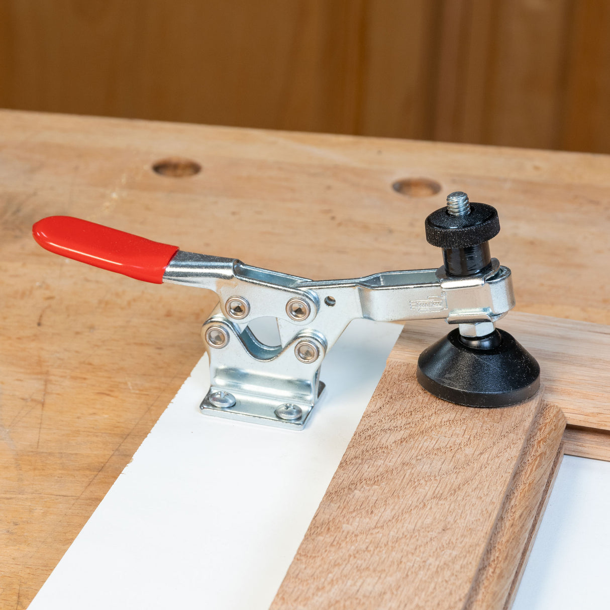 Infinity Tools medium toggle clamp mounted on a workbench holding a board in place
