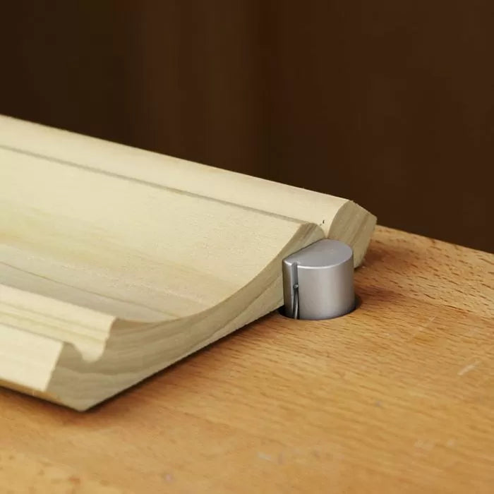 Woodworking jig holding a routed wood board on a workbench for precise cutting.