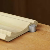 Woodworking jig holding a routed wood board on a workbench for precise cutting.