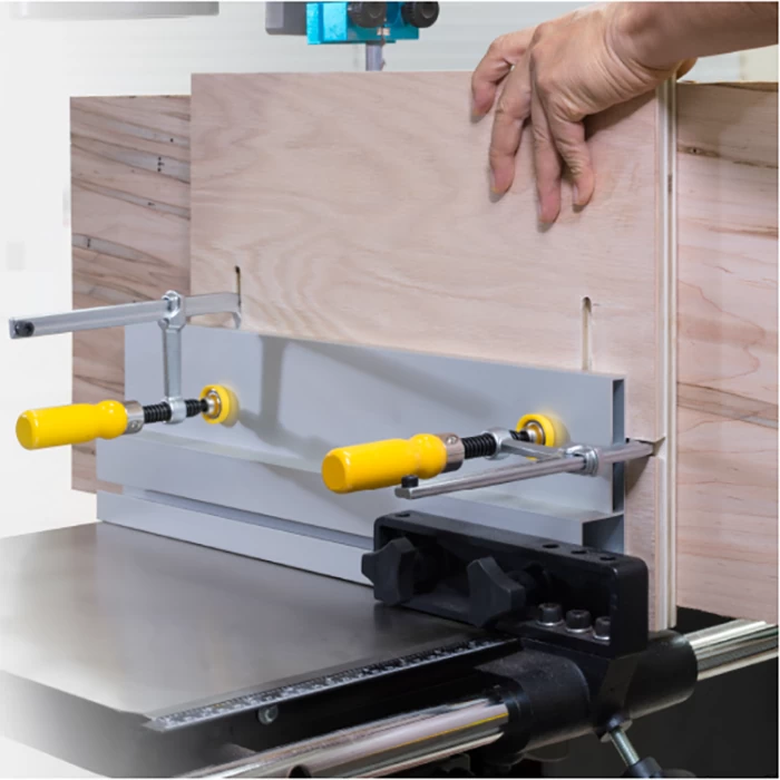 Woodworker using a bandsaw fence jig with yellow handles to cut precise grooves in wood