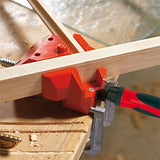 Woodworking corner clamp securing two boards at a right angle on a workbench