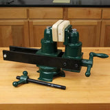 Green woodworking bench vise with wooden jaw on workbench in workshop setting