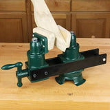 Green woodworking vise holding a wooden piece on a workbench for wood carving or shaping