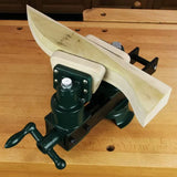 Woodworking vise securely clamping a curved wood piece on a workbench