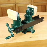 Green twin-screw woodworking vise with wood jaws on a workbench, ideal for clamping projects