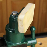 Woodworking bench vise with green metal body and wooden jaw pad attached