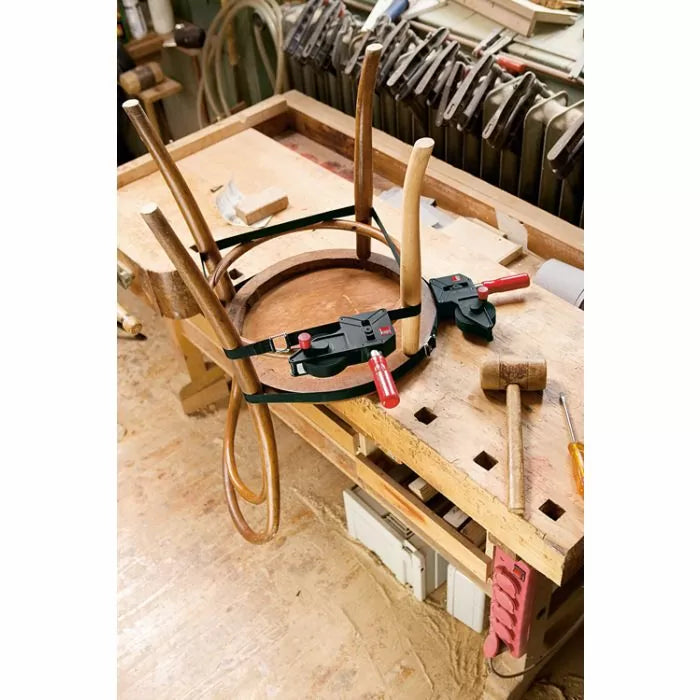 Woodworking band clamp securing a chair frame on a workbench in a woodshop