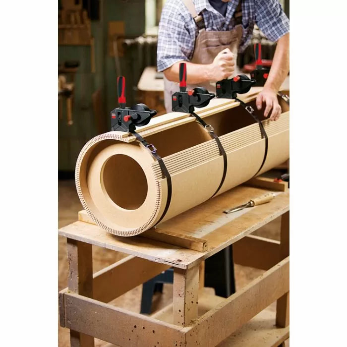 Woodworker using clamps to bend and glue cylindrical MDF form in woodworking shop