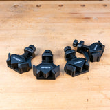 Set of four black corner clamps for woodworking on a wooden workbench surface