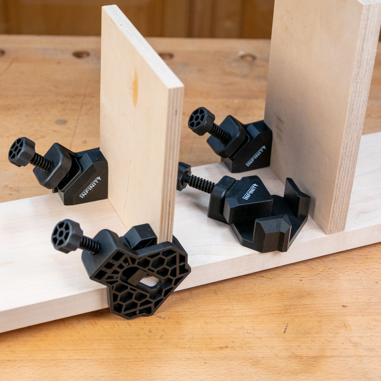 Corner clamps securing wood panels for precise woodworking joinery on a workbench