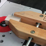 Woodworking router table with wooden hand screw clamp securing a wood block near router bit