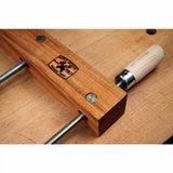 Wooden handscrew clamp with metal handles and screws on a woodworking bench