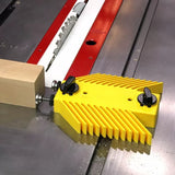 Yellow table saw featherboard securing wood for precise woodworking cuts