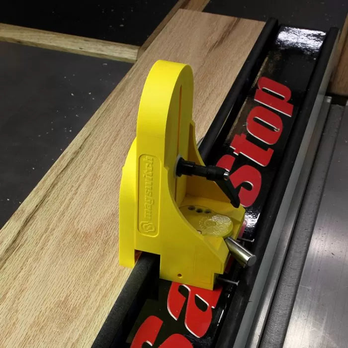 Yellow magnetic featherboard attached to table saw fence for precise woodworking