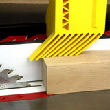 Yellow featherboard holding wood against table saw fence for safe, precise woodworking cuts