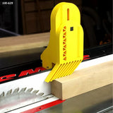 Table saw safety push block holding wood against fence with visible saw blade in workshop