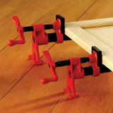 Red woodworking parallel clamps securing a wooden frame on a hardwood surface