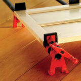 Woodworking pipe clamp holding a cabinet door panel on a hardwood floor
