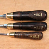 Set of three woodworking screwdrivers with dark wood handles and brass ferrules on a wood surface