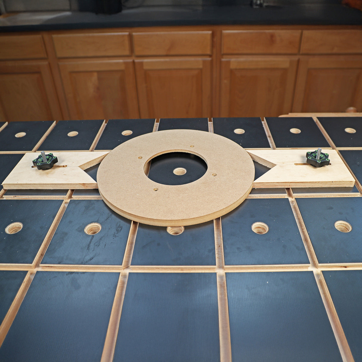 Woodworking circle cutting jig on workbench with cabinetry in background