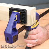 Quick-Grip clamp with optional wide pads securing a wood block on a workbench