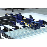 Assortment of blue woodworking clamps and pipe clamps on a white workshop table