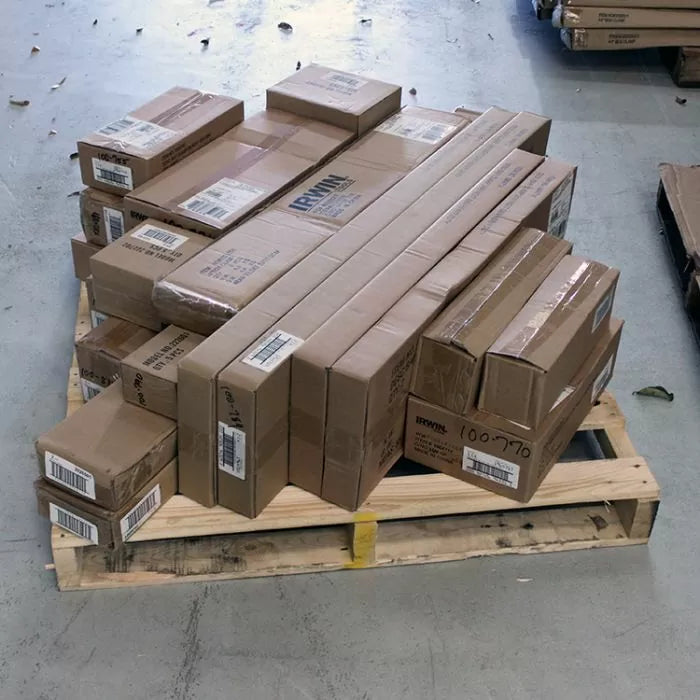 Stacked cardboard boxes of woodworking tools and accessories on a pallet in a warehouse