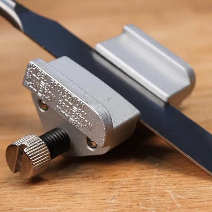Sharpening jig attached to a chisel blade on a wooden workbench