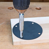 Drill with self-centering bit making a pilot hole in a router table insert plate on wood